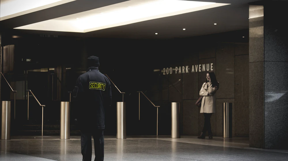 Security guard in a high-visibility jacket walking across an open plaza