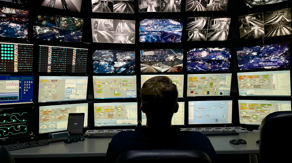 Security operator monitoring a wall of live CCTV camera feeds in a control room